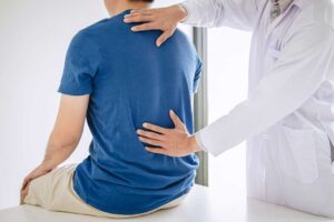 Clinician performing a controlled spinal adjustment while a patient lies on a treatment table.