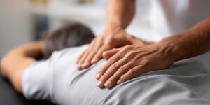 Person gently stretching a shoulder beside a window with a foam roller and anatomy notes nearby